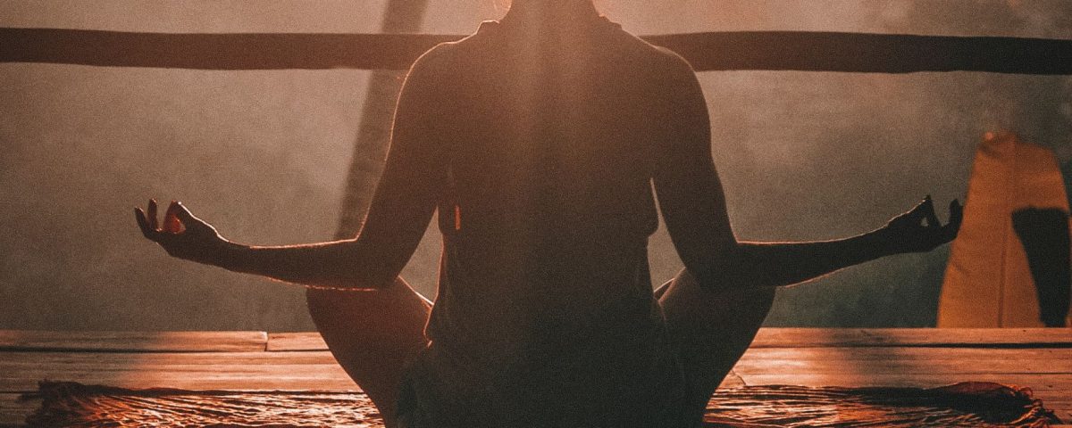 human meditating on wooden deck at sunrise