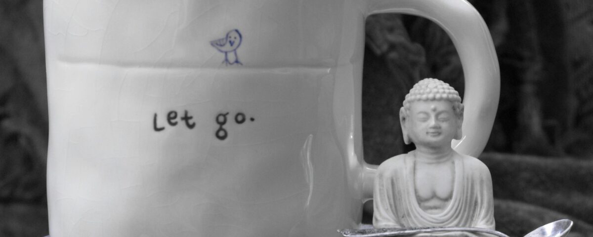 buddha statuette and mug with "Let go" written on it, on top of books